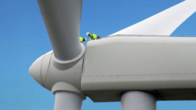 Workers in PPE work on the nacel of a wind turbine