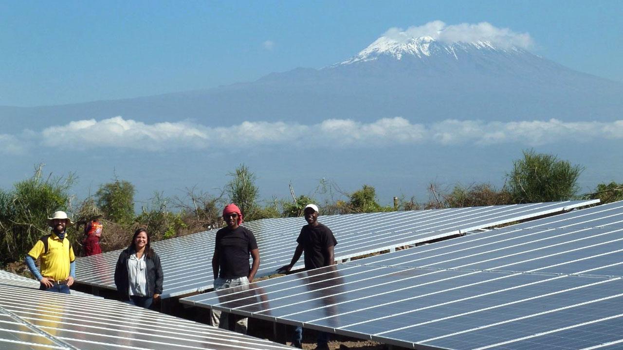 Group of solar engineers stand in a solar panel field at the base of Mt. Kilimanjaro as part of the Tetra Tech-led Power Africa program