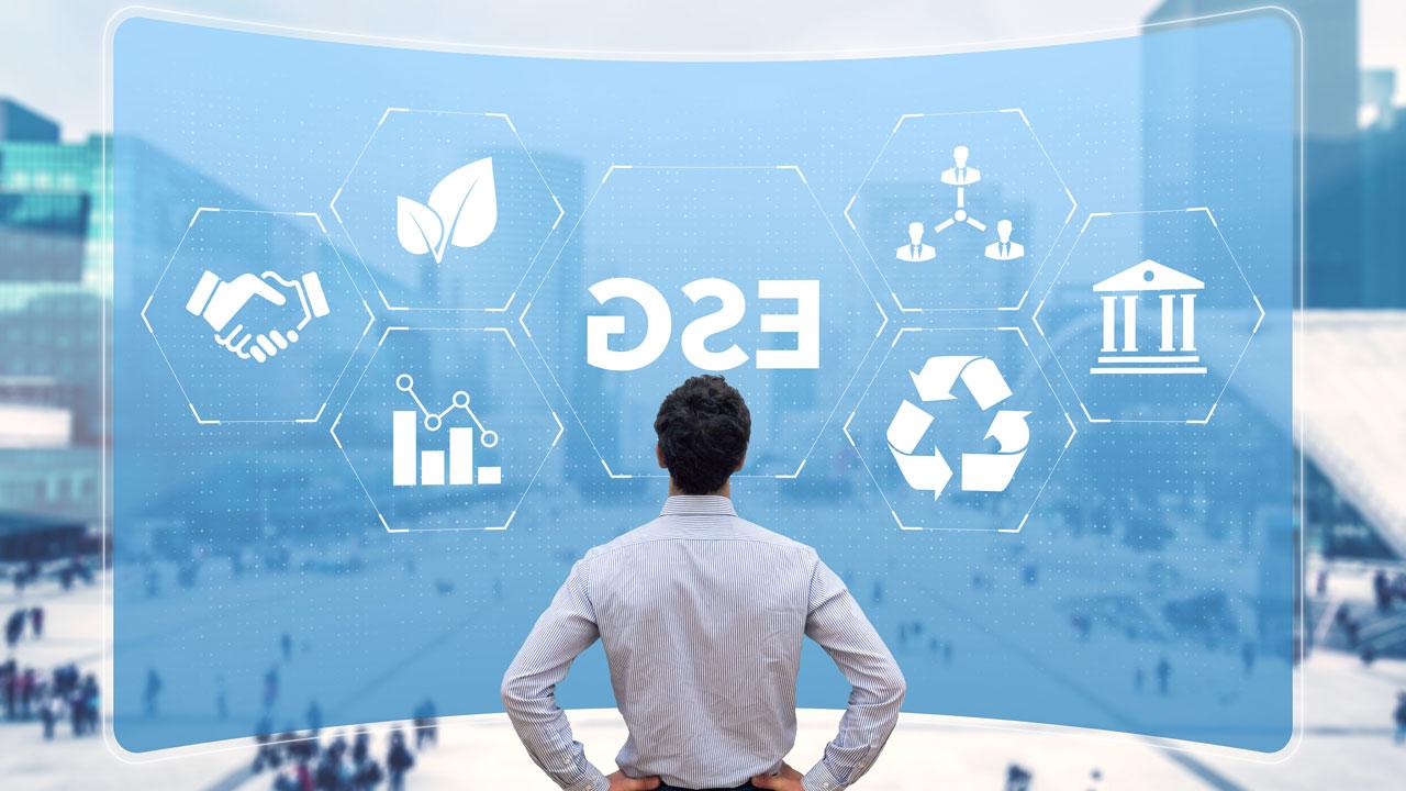 一名男子站在蓝色投影背景前，背景上有ESG字母和代表环境的各种图标, 社会, 和治理