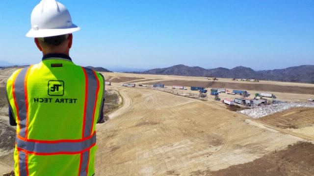 Tetra Tech employee wearing a hard hat and safety vest overseeing waste disposal practices at a landfill